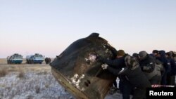 Ground personnel roll the Soyuz TMA-02 capsule after it landed while carrying ISS crew members near the town of Arkalyk, Kazakhstan.