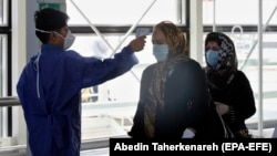 A man checks the temperature of passengers at Imam Khomeini International Airport outside Tehran on July 17.