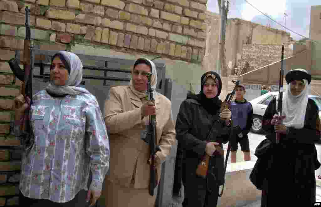 Armed members of the Women&#39;s Association linked to the ruling Ba&#39;ath party stand at the entrance to their party&#39;s building in Baghdad on March 23.