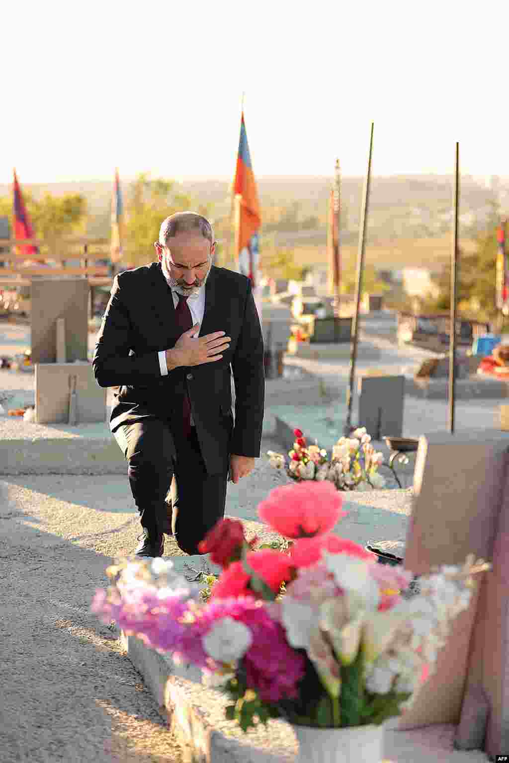 Armenian Prime Minister Nikol Pashinian kneels in the Yerablur Military Memorial Cemetery in Yerevan early on September 27 as commemorations of the 2020 fighting begin.