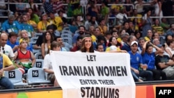 A woman holds a banner reading "Let Iranian women enter their stadiums" during a volleyball match between Russia and Iran in Rio de Janeiro on August 2016 during the Rio 2016 Olympic Games.