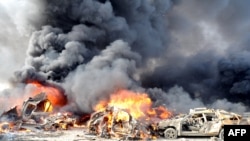 Smoke rises from burning cars at the site of twin blasts in Damascus on May 10.