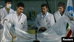 Iranian President Mahmud Ahmadinejad (center) looks on as scientists unveil a fuel rod at the Tehran Research Reactor.