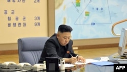 North Korean leader Kim Jong Un at an undisclosed location, sitting in front of a map that appears to show the tracked or projected movement of the U.S. Seventh Fleet in the Pacific Ocean