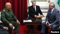 Venezuela's then-President Hugo Chavez (left) and Belarusian envoy Viktar Sheiman (right) talk during a meeting in Caracas in October 2011.