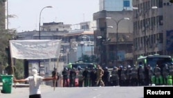 A Syrian antiregime protester faces riot police at Khalidia, near Homs.