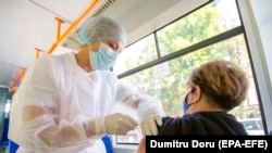 A health worker administers a dose of vaccine against COVID-19 to a woman on a trolleybus used as a mobile vaccination point in Chisinau.