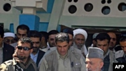 Afghan President Hamid Karzai (right) arrives in the village of Azizabad in the district of Shindand.