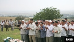 People pray during the burial of murdered human rights activist Natalya Estemirova at a cemetery in Koshkeldy, 70 kilometers east of Grozny, on July 17, 2009.