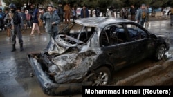 People look at a damaged vehicle after a deadly suicide bomb attack in Kabul on November 16.