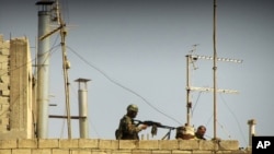 An image provided to AP by a citizen jouralist in May of Syrian soldiers on the roof of a building at an undisclosed location.