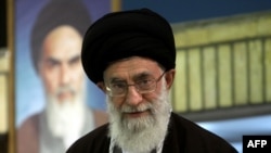 Iran's Supreme Leader Ayatollah Ali Khamenei, standing in front of a portrait of the late founder of the Islamic republic, Ayatollah Ruhollah Khomeini