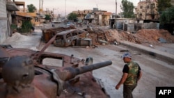 A member of the Free Syrian Army walks past a destroyed government tank in the town of Atareb in northern Aleppo province.