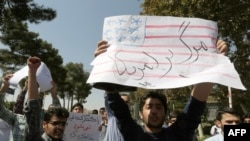 Hard-line supporters of Iran's Basij militia raise up anti-American placards as Iranian president Hassan Rouhani's motorcade leaves Tehran's Mehrabad Airport upon his arrival from New York on September 28.